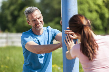 Couple doing stretching excersice on pole - DIGF04350