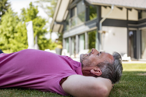 Älterer Mann liegt im Garten seines Hauses, lizenzfreies Stockfoto