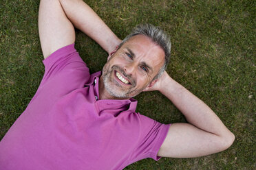 Porträt eines lächelnden reifen Mannes im Gras liegend - DIGF04373