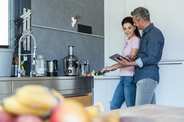 Couple in kitchen at home using a tablet - DIGF04438