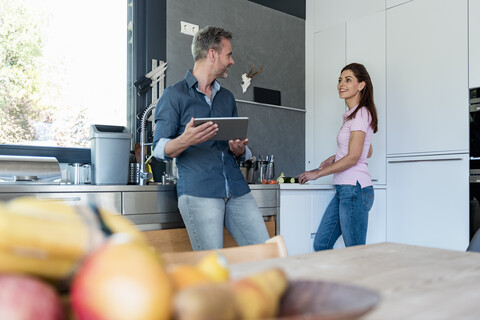 Couple in kitchen at home cooking and using a tablet stock photo