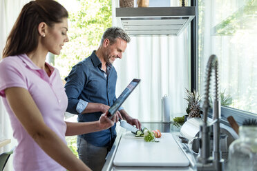 Paar in der Küche zu Hause beim Kochen und mit einem Tablet - DIGF04444