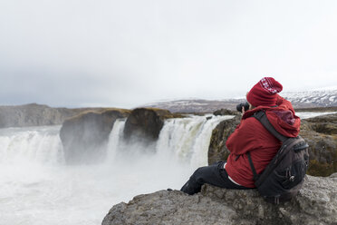 Island, Nordisland, junger Mann fotografiert Wasserfall - AFVF00531