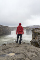 Iceland, North of Iceland, young man looking to waterfall - AFVF00533