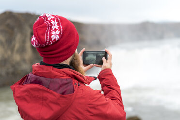 Island, Nordisland, junger Mann fotografiert Wasserfall - AFVF00536