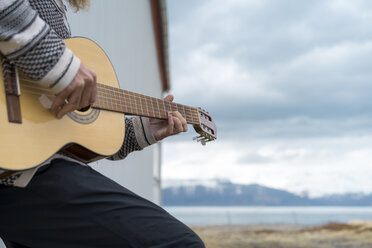 Island, junger Mann spielt Gitarre - AFVF00539