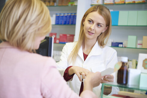 Portrait of pharmacist advising woman in pharmacy - ABIF00393