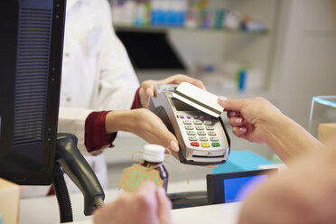 Customer paying cashless with credit card in a pharmacy - ABIF00398