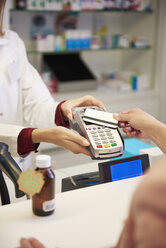 Customer paying cashless with credit card in a pharmacy - ABIF00399
