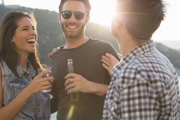 Three adult friends laughing and partying on roof terrace - ISF02203