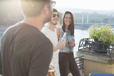 Drei erwachsene Freunde beim Feiern auf einer Dachterrasse am Wasser, Budapest, Ungarn - ISF02207