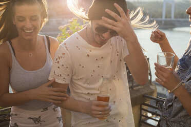 Young couple at windy waterfront roof terrace party, Budapest, Hungary - ISF02238