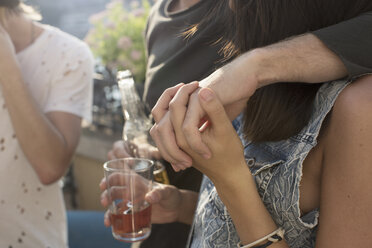 Cropped shot of couple holding hands at roof terrace party - ISF02242