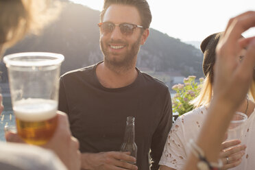 Adult friends partying with drinks on waterfront roof terrace - ISF02247