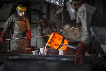 Metallarbeiter in der Gießerei, die geschmolzene Bronze gießen - ISF02254