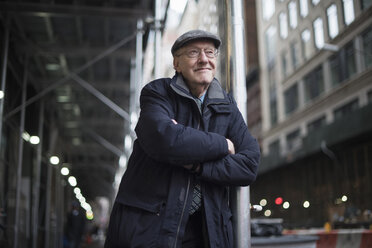 Man, arms crossed leaning against lamppost, Manhattan, New York, USA - ISF02306