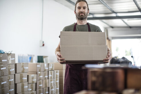 Portrait of man holding cardboard box in factory - ISF02314