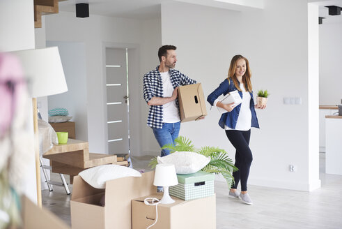 Ehepaar zieht in eine neue Wohnung ein und trägt Karton und Pflanze - ABIF00423