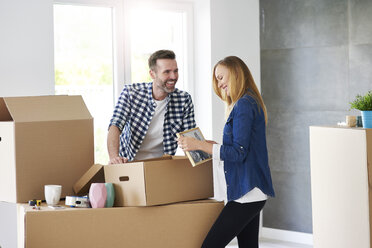 Couple moving into new flat packing cardboard boxes - ABIF00425