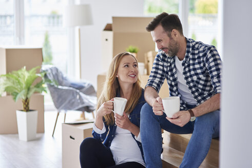 Mann und schwangere Frau ziehen in eine neue Wohnung ein und machen eine Kaffeepause - ABIF00429