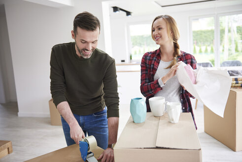 Ehepaar, das umzieht und Kartons verpackt und mit Klebeband befestigt - ABIF00444