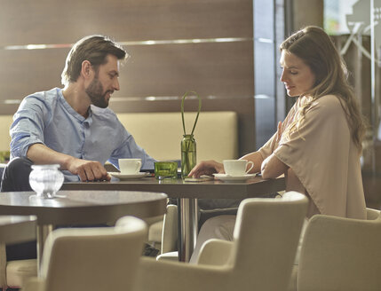 Mann und Frau sitzen am Tisch und trinken Kaffee - CVF00569