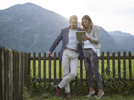 Mann und Frau teilen sich ein Tablet in einer ländlichen Landschaft - CVF00584