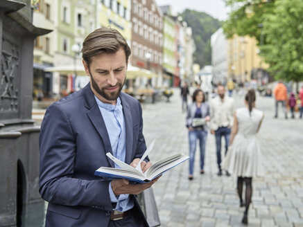 Geschäftsmann beim Lesen eines Buches in der Stadt - CVF00605