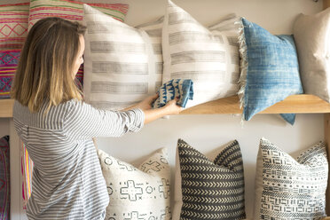 Rear view of female interior designer trying textile against cushions in retail studio - ISF02354