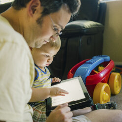 Vater und kleiner Sohn schauen auf ein digitales Tablet - ISF02369