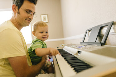 Father and young son playing musical keyboard together - ISF02370