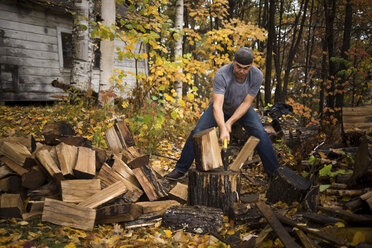 Mittlerer erwachsener Mann beim Holzspalten im Herbstwald, Upstate New York, USA - ISF02400