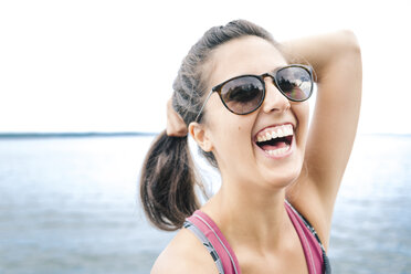 Junge Frau mit Sonnenbrille lachend am Meer, Maine, USA - ISF02402