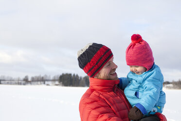 Vater hält seinen kleinen Sohn in einer verschneiten Landschaft - ISF02410