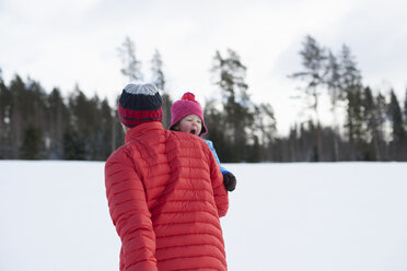 Vater trägt kleinen Sohn in verschneiter Landschaft - ISF02417