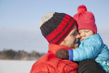 Father carrying young son in snow covered landscape - ISF02422