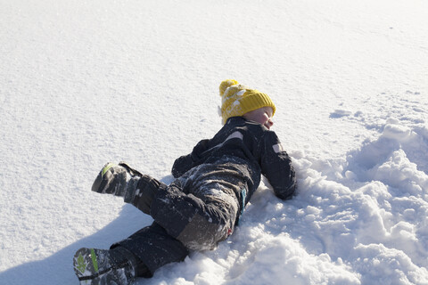 Junger Junge, der im Schnee herumalbert, lizenzfreies Stockfoto