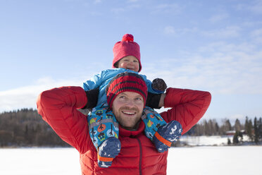 Father carrying young son on shoulders, in snow covered landscape - ISF02430