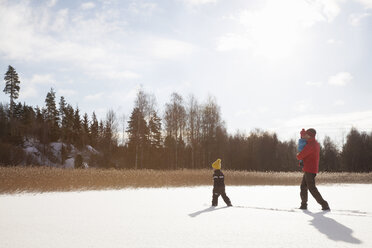 Vater und zwei Söhne, die durch eine verschneite Landschaft wandern - ISF02433