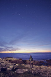 Hiker gazing at the Big Dipper from rocks, Fogo Island, Newfoundland, Canada - ISF02443