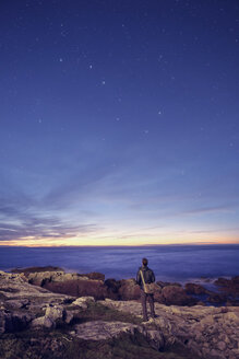 Hiker gazing at the Big Dipper from rocks, Fogo Island, Newfoundland, Canada - ISF02443