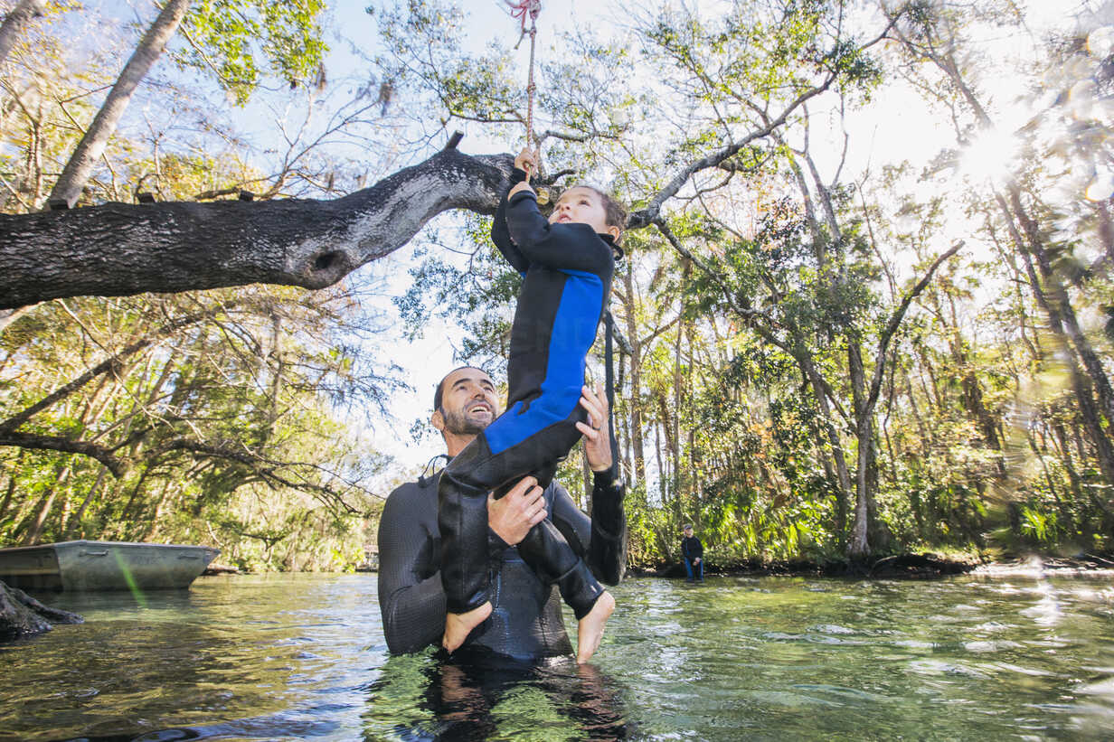 Father in river helping daughter with rope swing on tree, Chassahowitzka,  Florida, USA stock photo