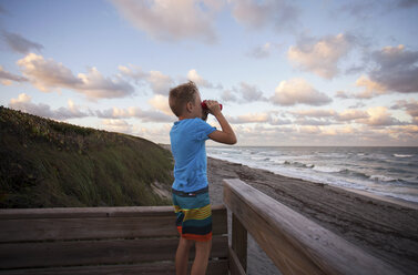 Boy at beach looking at view through binoculars, Blowing Rocks Preserve, Jupiter, Florida, USA - ISF02471