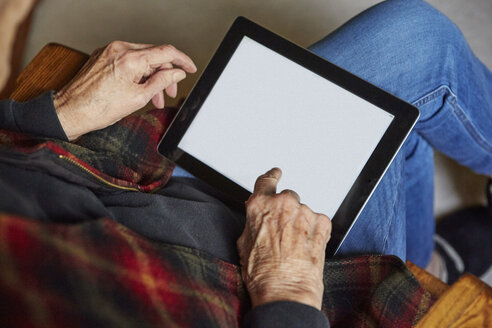 Ältere Frau auf einem Stuhl sitzend, mit digitalem Tablet, Blick von oben - ISF02478