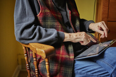 Ältere Frau auf einem Stuhl sitzend, mit digitalem Tablet, Mittelteil - ISF02479