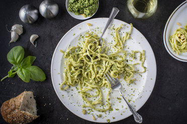 Ein verzehrter Teller mit Pesto-Pasta, die Zutaten um den Teller herum und ein Glas Weißwein, Blick von oben - ISF02482