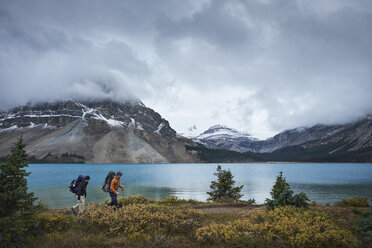 Hikers hiking by lake and snow capped mountains, Banff, Alberta, Canada - ISF02508