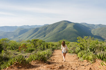 Frau, die einen unbefestigten Weg entlangläuft, Rückansicht, Hierve el Agua, Oaxaca, Mexiko. - ISF02557