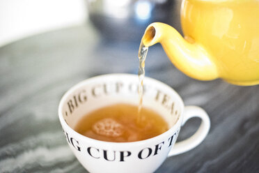 Tee aus einer Teekanne in eine Teetasse gießen - ISF02577