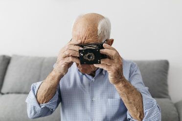 Älterer Mann, der ein Foto mit einer alten Fotokamera macht - JRFF01666